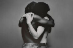 Black and white photo of interracial gay couple embracing.